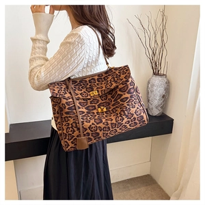 Detail of leopard print tote bag featuring dual gold twist locks and leather straps