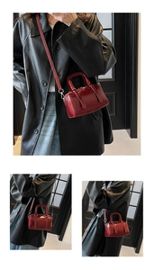 Close-up of deep red Boston handbag with leather texture and silver hardware accents