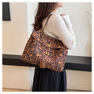 Close-up of leopard print tote bag with brown leather straps and gold metal buckles