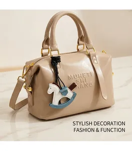 Detail of beige tote bag with embossed letters and a Trojan horse leather charm pendant