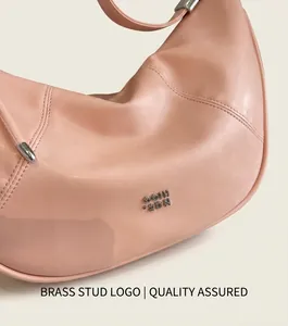 Detail der rosa Ledertextur und des Metalllogos auf der modischen Halbmondtasche