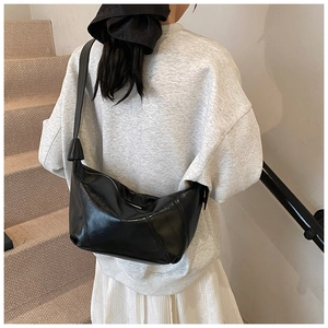 Close-up of black pleated faux leather hobo bag with moon shape and stitched details