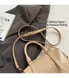 Detail of beige textured leather handbag with gold hardware on a grey blazer suit