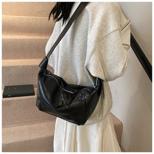 Detail of black faux leather croissant bag with knotted strap shown in lifestyle setting