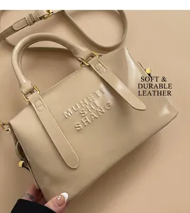 Close-up of beige handbag with embossed logo detail and gold-tone metal hardware