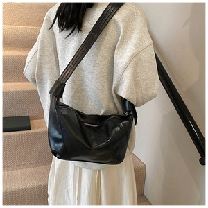 Detail of the black glossy hobo bag featuring a stylish knotted wide shoulder strap design