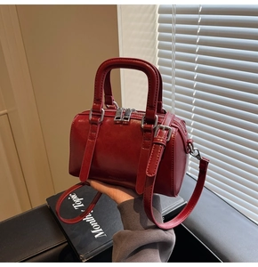 Detail of red leather Boston bag showing smooth texture and adjustable shoulder strap