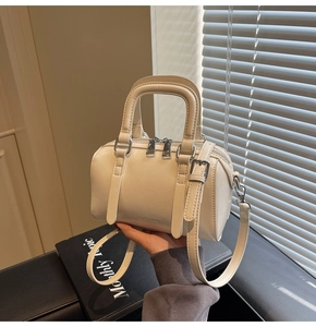 Close-up of beige Boston handbag featuring textured leather and silver hardware details