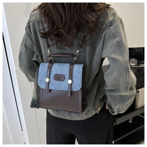 Detail eines Rucksacks aus braunem Leder und blauem Denim mit goldenen Nieten