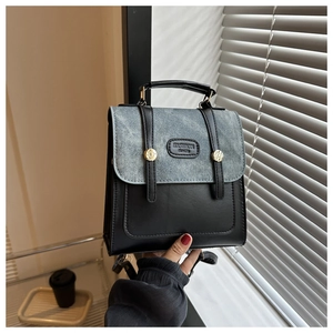 Detail der grauen Denim-Klappe und schwarzen Lederrucksack mit goldener Ringschnalle