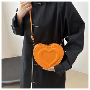 Détail du sac à bandoulière orange en forme de cœur avec motif en cuir gaufré texturé