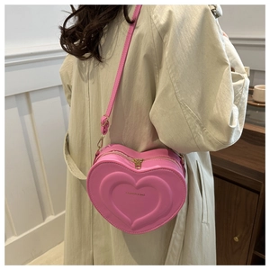 Vue arrière du mannequin portant le sac bandoulière coeur en cuir rose et zip doré