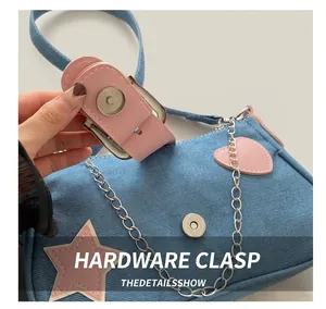 Dettaglio della fibbia magnetica argentata su una borsa in denim con stelle rosa