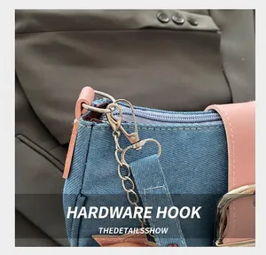 Dettaglio del gancio in metallo argento e pelle rosa su una borsa in denim