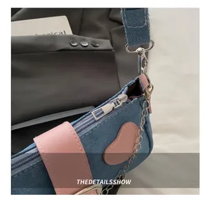 Dettaglio della borsa a tracolla in denim blu con finiture in pelle rosa e zip argentata