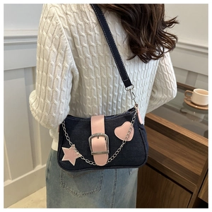 Dettaglio borsa a tracolla in denim con toppa stella rosa e catena metallica