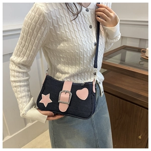 Dettaglio della borsa a tracolla in denim con toppa a stella rosa e fibbia in metallo