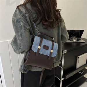 Zaino in pelle marrone e denim blu indossato da una modella in interni moderni