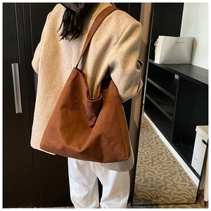 Brown suede tote bag with a soft slouchy design shown in a casual lifestyle shoulder shot