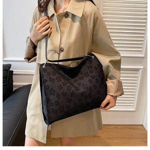 Détail du sac cabas noir à fleurs gaufrées et anneaux argentés sur un mannequin