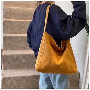 Side view of large mustard yellow suede hobo shoulder bag styled on a female model