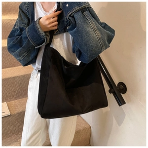 Detail of minimalist black oversized hobo bag with a matte texture on a female model