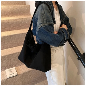 Overhead view of a large black minimalist tote bag worn with a denim jacket on stairs