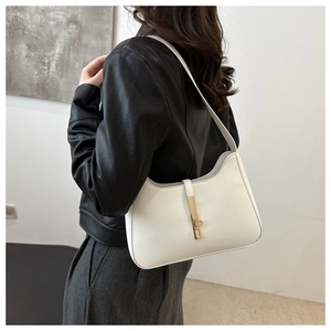 Close-up of white leather hobo bag with gold piston clasp worn by a model in leather jacket