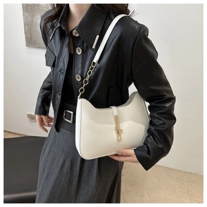 Detail view of the sleek white underarm bag with gold metal clasp and chain strap