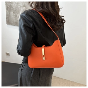 Detail of a bright orange leather underarm bag with signature gold vertical metal buckle