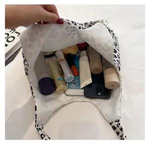 Top view of spacious interior of leopard print tote bag with cosmetics and phone