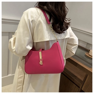 Detail of hot pink crescent bag with golden metal lock and leather chain strap