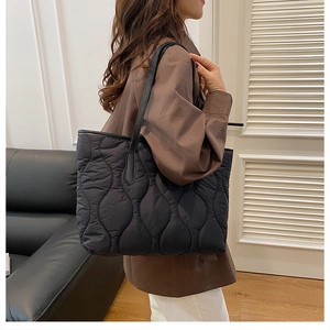 Detail der schwarzen Stepptasche mit Wellenmuster und schmalem Schultergurt aus Nylon