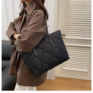 Nahaufnahme des gesteppten Wellenmusters einer schwarzen Damenhandtasche am Model