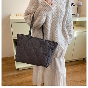 Detail of grey quilted tote bag with wave stitching and slim black leather handles