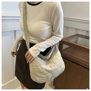 Detail of beige quilted tote bag with heart embroidery and soft padded nylon texture