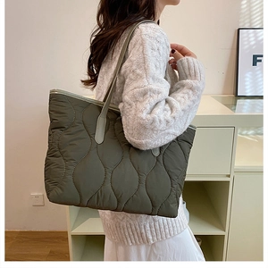 Détail du grand sac cabas matelassé vert olive avec motif à vagues porté par un modèle