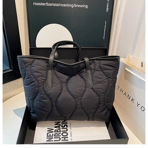 Detail of black quilted puffer tote bag displayed in a stylish urban setting