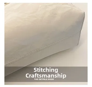 Détail de couture double précise sur le sac cabas blanc perle en cuir à texture plissée