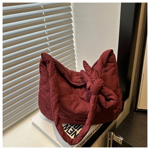 Detail of burgundy quilted nylon hobo bag with wave patterns and knot shoulder strap