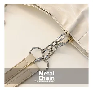 Gros plan de la chaîne argentée polie et du cuir texturé d'un sac cabas beige