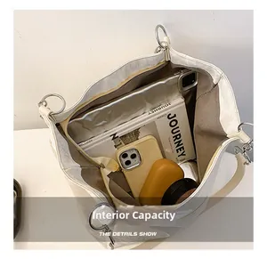 Vue de dessus montrant la grande capacité interne du cabas en cuir beige avec accessoires