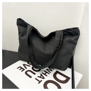 Detail of a large dark grey denim tote bag showing wide straps and natural fabric texture