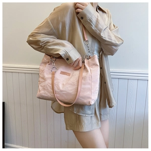 Détail du sac cabas plissé rose avec étiquette en cuir et anneau métallique de bandoulière