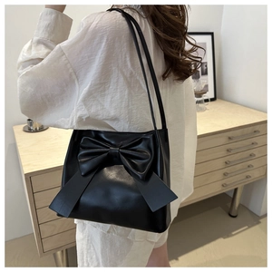 Detailed view of black PU leather tote bag featuring a large bow and slim shoulder straps