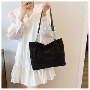 Détail du sac cabas noir avec texture en cuir froncé et étiquette mode sur le devant