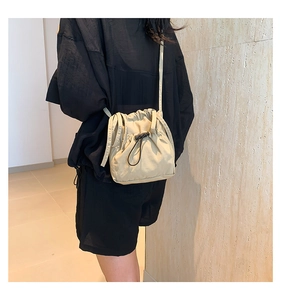 Detailed back view of a beige drawstring crossbody bucket bag in light nylon material