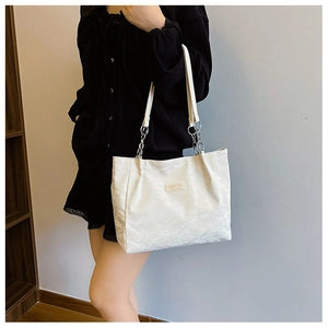 Détail du sac cabas blanc avec texture plissée et chaîne métallique sur la bandoulière