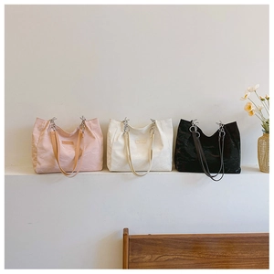 Trois sacs cabas texturés en rose, blanc et noir avec détails de chaîne métallique