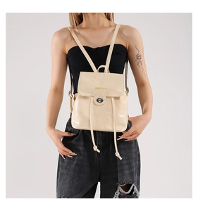 Detail of beige faux leather backpack showing silver twist lock and drawstring closure